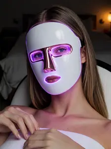 Woman relaxing at home while wearing the Lumoras LED face mask in purple light mode